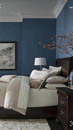 a bedroom painted in blue and white with a bed, nightstands, and painting on the wall