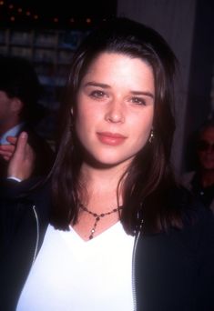 a woman with long dark hair wearing a white shirt and black jacket at an event