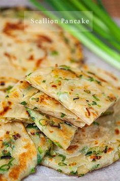 several flatbreads stacked on top of each other with green onions in the background