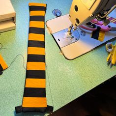 the sewing machine is next to an orange and black striped tie