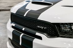 the front end of a white truck with black and white stripeing on it's hood