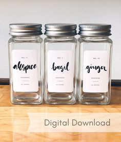 three glass jars with labels on them sitting on a wooden countertop next to each other