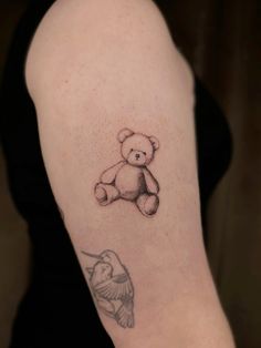 a woman with a tattoo on her arm has a small teddy bear and humming bird