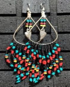 Handmade beaded drop hoop earrings.  Silver with a Feather charm hanging in the center.  Beads are black, red, turquoise, and yellow.  Hang approximately 3.5 to maybe 4 inches long.  Would look beautiful with clothing of all those colors. Bohemian Black Hoop Earrings With Dangling Beads, Multicolor Dangle Jewelry With Black Beads, Black Dangle Hoop Earrings For Festivals, Multicolor Teardrop Hoop Earrings With Dangling Beads, Bohemian Black Earrings With Large Beads, Black Dangle Jewelry With Large Beads, Hoop Dangle Earrings, Drop Hoop Earrings, Hoop Earrings Silver