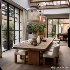 a dining room table with chairs and lights hanging from it's centerpieces