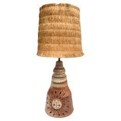 a lamp that is sitting on top of a wooden base with a light shade over it