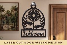 a welcome sign is hanging on the wall next to a potted plant and door