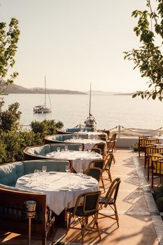 tables with white tablecloths are lined up near the water