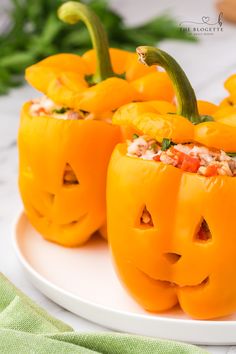 three peppers with faces carved into them on a plate