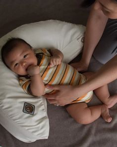 a woman holding a baby on top of a pillow