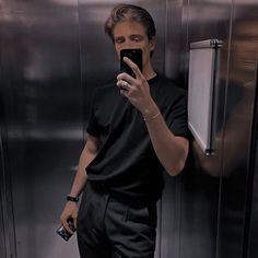 a man taking a selfie with his cell phone in front of an elevator door