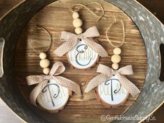 three cookies decorated with wooden beads and bows are in a metal pan on a table