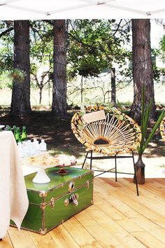 a green trunk sitting on top of a wooden floor next to a white table cloth