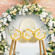 an arch decorated with flowers and beehive signs for a baby's first birthday