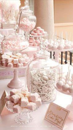 a table topped with lots of candy covered in white and pink candies on top of glass containers