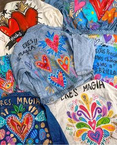 several jean jackets with colorful designs on them