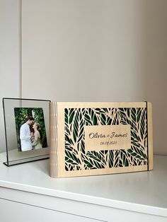 a couple's wedding album is sitting on a shelf next to an empty photo frame