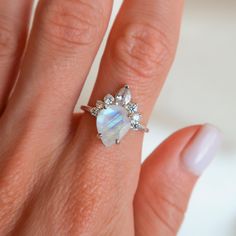 a woman's hand wearing a ring with an opalite and diamond center