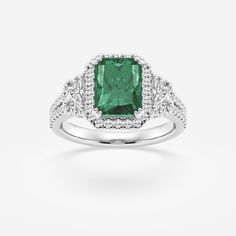 an emerald and diamond ring on a white background