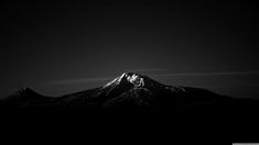 a black and white photo of the top of a mountain in the night sky with clouds