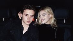 a young man and woman sitting in the back of a car at night, posing for a photo