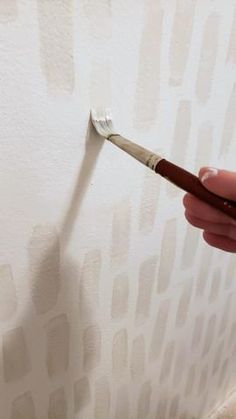 a person is holding a paintbrush in their hand and painting the wall with white paint