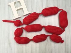 crocheted lobsters are laying next to the letter h on a white table