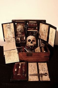 an open wooden box filled with lots of different items on top of a black table