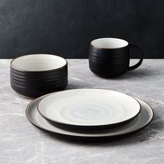 two black and white plates, one with a saucer and the other with a cup