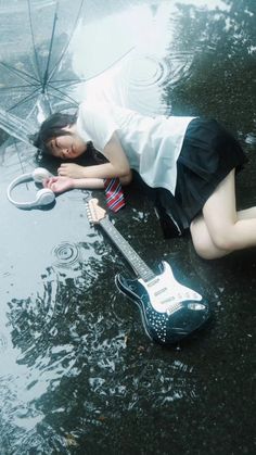 a woman is laying on the ground with an umbrella and guitar in her hand,