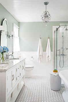 a bathroom with two sinks, a tub and a chandelier hanging from the ceiling