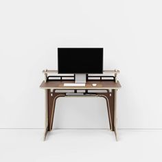 a desk with a computer on top of it in front of a white wall and floor