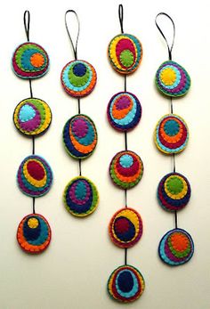 several colorful crocheted circles hanging from strings on a white wall in the shape of an ornament