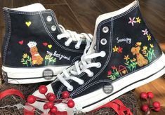 a pair of black shoes with embroidered teddy bears on them and red berries in the foreground