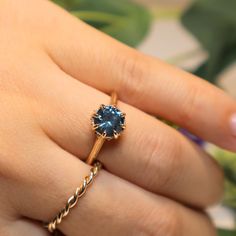 a woman's hand holding a ring with a blue stone