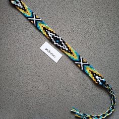 a blue, yellow and black braided bracelet with a tag on the bottom of it