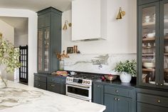 a kitchen with marble counter tops and green cabinetry in the backround area