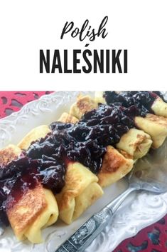 a white plate topped with crepes covered in blueberry sauce