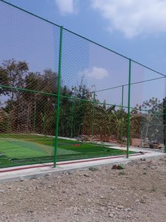 a baseball field behind a fence with grass on the ground and dirt in front of it