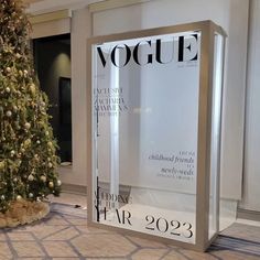 a christmas tree in front of a window with the cover of a magazine on it