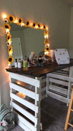 a desk made out of pallet wood with sunflowers on the top and lights around it