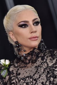 lady in black and white makeup at the oscars with flowers on her head, looking off to the side