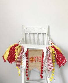 a white chair with a red and yellow one banner on it's back sitting in front of a white wall