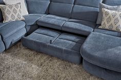 a blue sectional sofa with two pillows on the back and one arm facing it's headrests