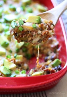 a spoon full of food is being lifted from a casserole dish with meat and vegetables