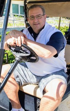 a man sitting in the driver seat of a golf cart with his hand on the steering wheel