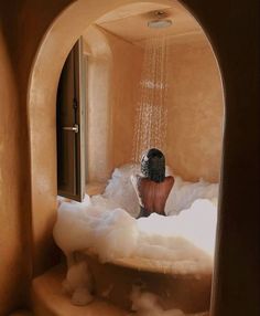 a person sitting in a bubbley bathtub with water coming out of the shower head