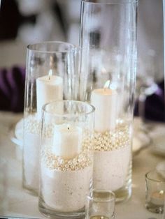 some candles are sitting in glass vases on a table