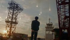 a man standing on top of a roof next to a tower with lots of lights