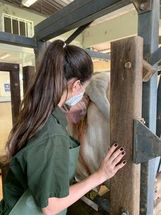 a woman wearing a face mask petting a cow